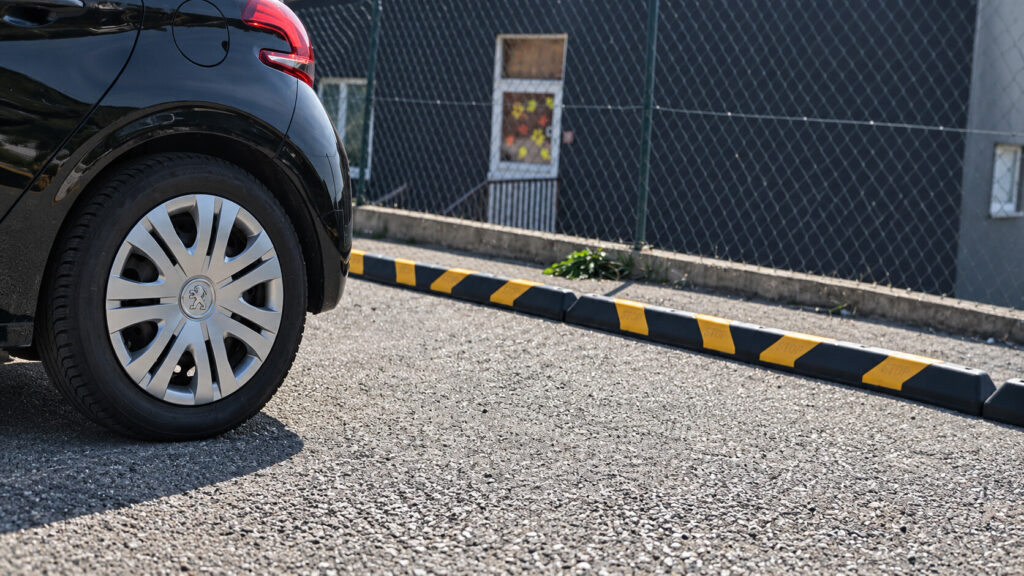Crni automobil uz crno-žuti gumeni graničnik
