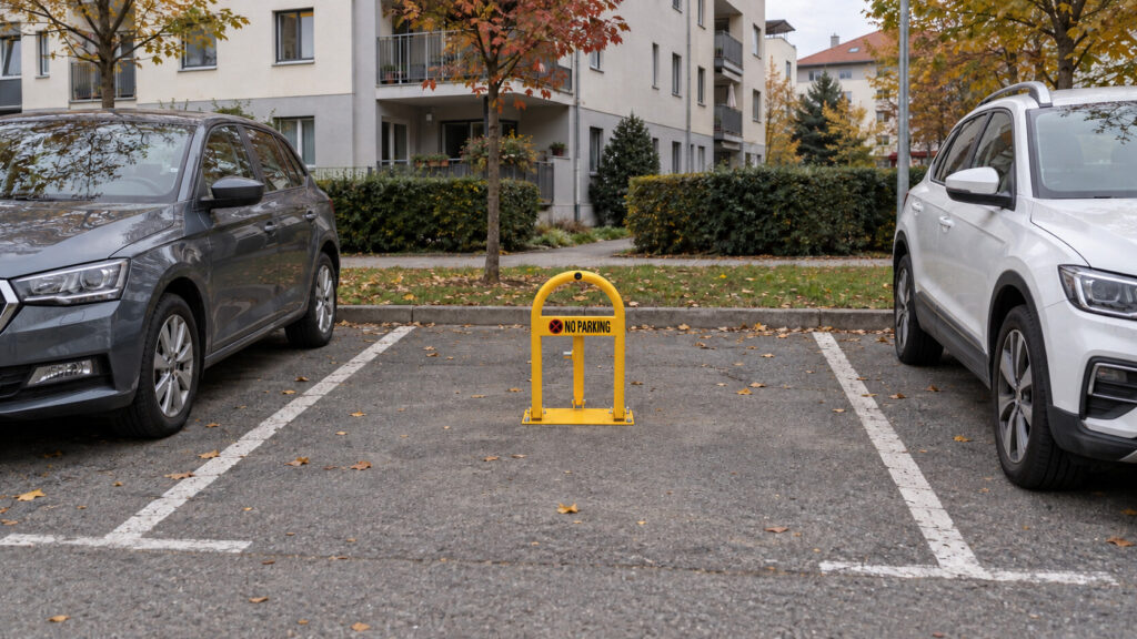 Žuta parking barijera između dva parkirana automobila